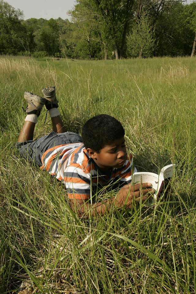 Young boy lays comfortably on a field of grass