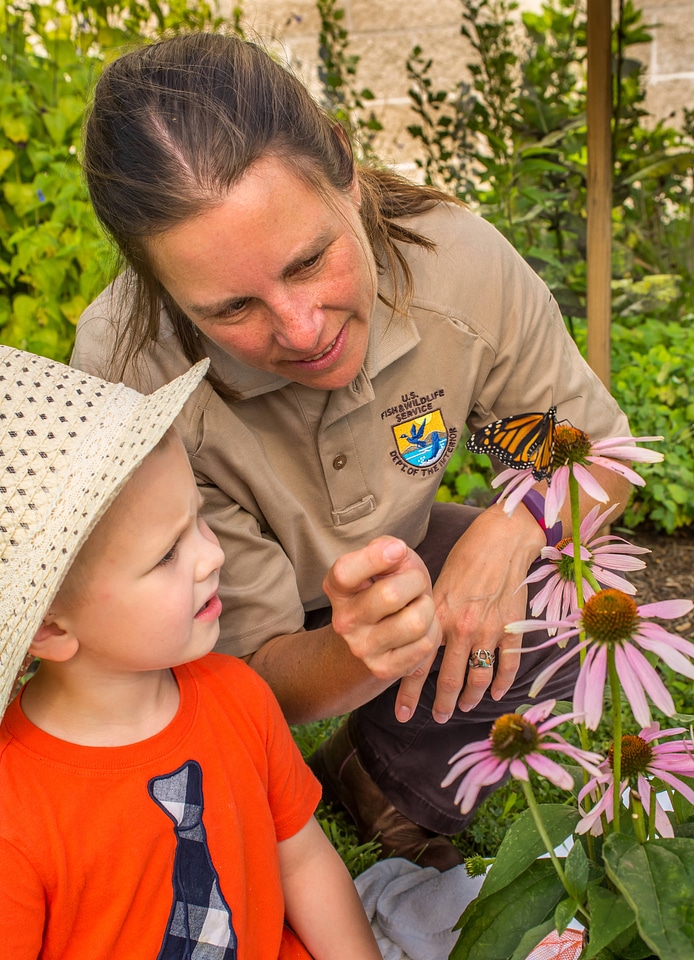 FWS employee and child looking at monarch