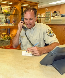 FWS Staffer at visitor center desk on phone