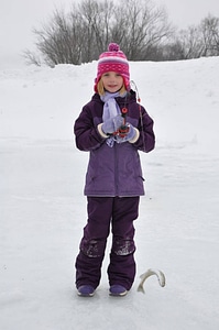 Young girl catches fish during ice fishing day photo