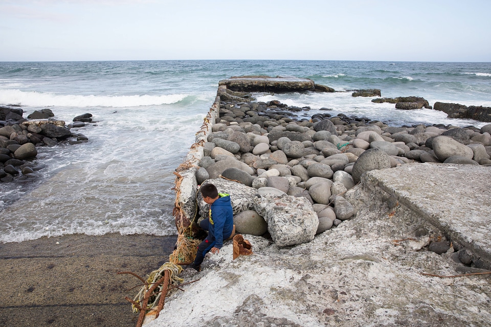 Child sits on the remains of the East Landing boat launch