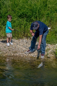 Boy fishing, older man nets rainbow trout