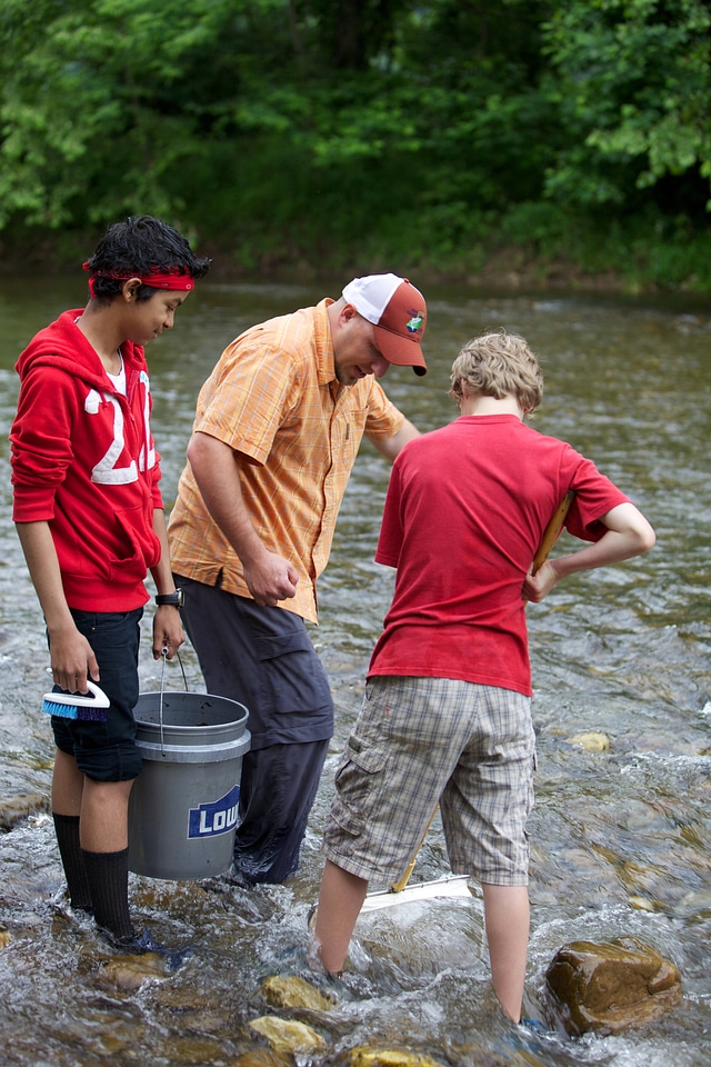 Educator and students collecting macroinvertebrates