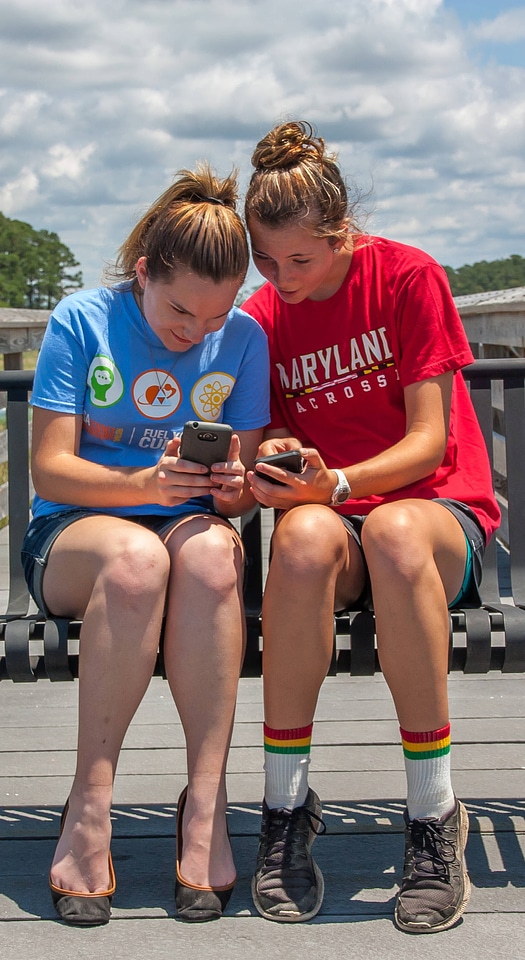Students sittting on bench sharing cell phone pictures-1