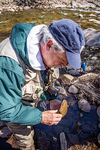 Fisherman examining rock in creek bed