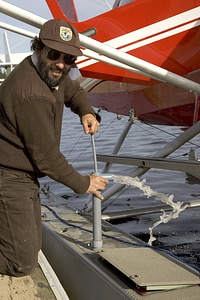Service employee hand-pumping water by a sea plane