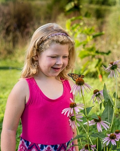 Little girl looking at butterfly on flower
