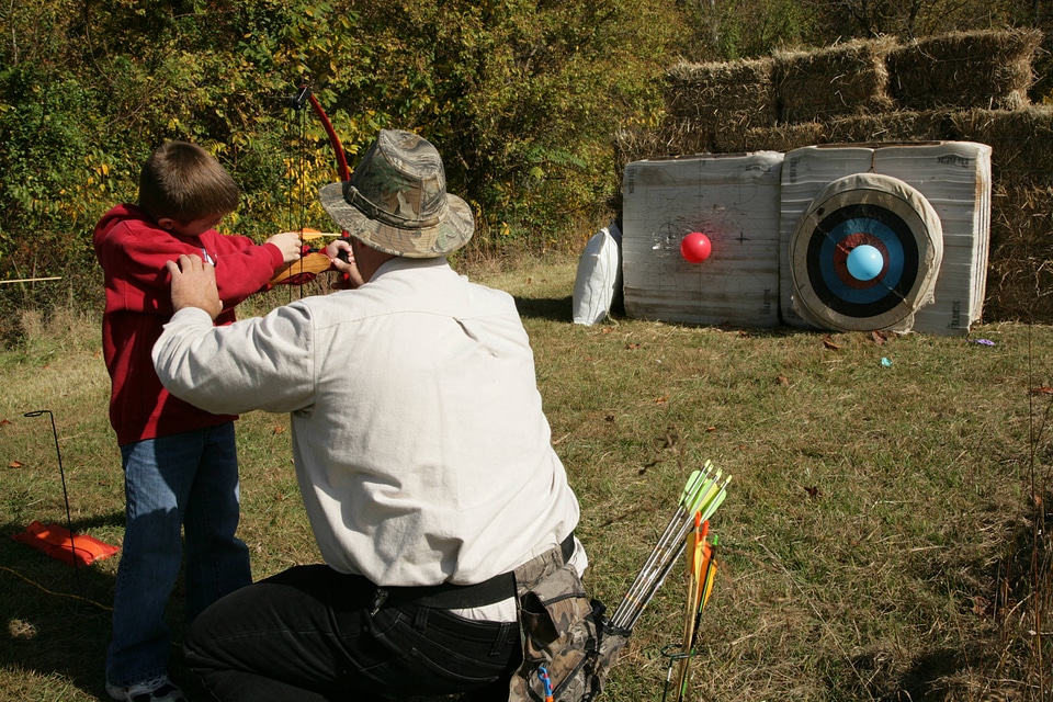 Adult teaching archery to a young boy-1