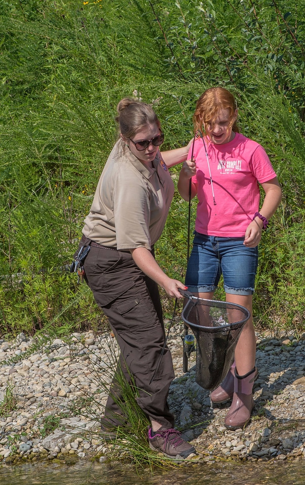 Young redheaded girl fishing, FWS employee netting trout