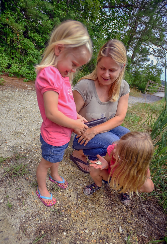 Mother helps young girls take picture of shell
