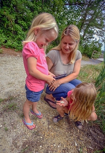 Mother helps young girls take picture of shell photo