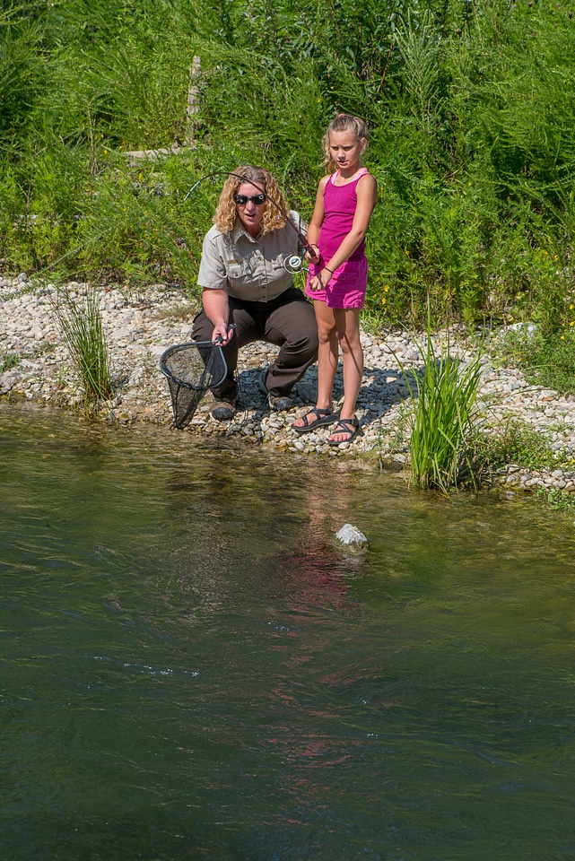 Young girl fishing, FWS employee netting rainbow trout-3