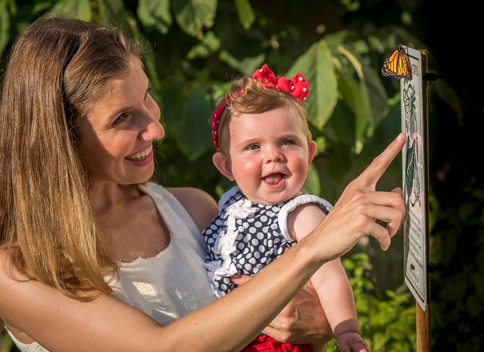 Mother and daughter look at monarch on sign