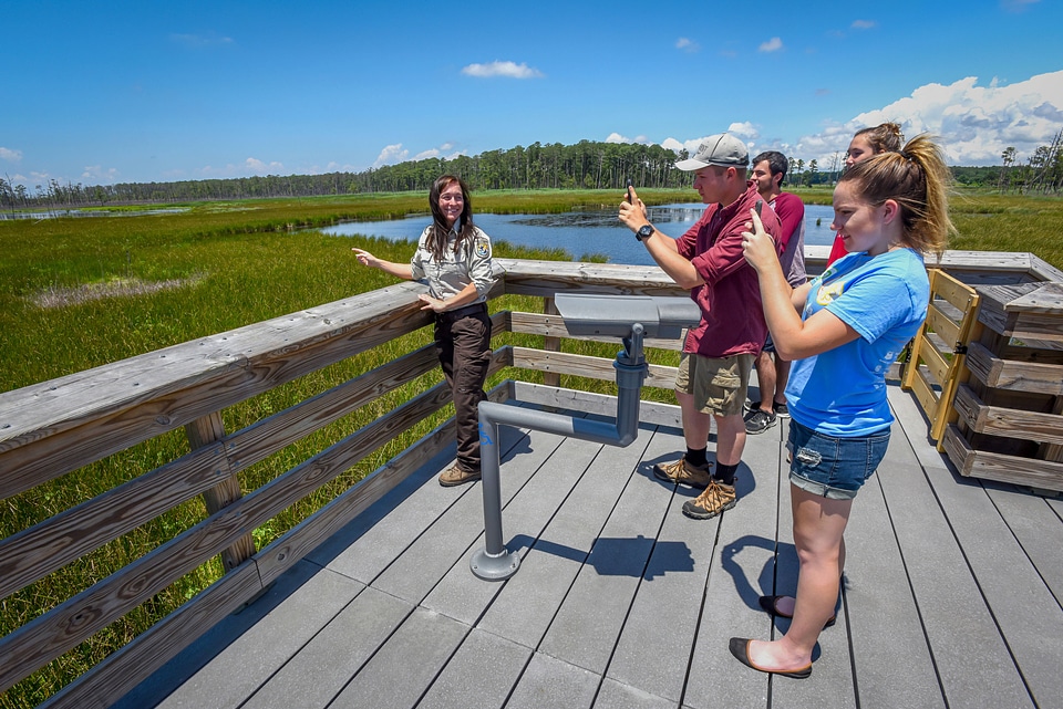 FWS Staffer shows young students wetland as they take cell phone pictures