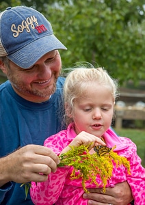 Father and daughter with monarch butterfly on goldenrod flowers-2