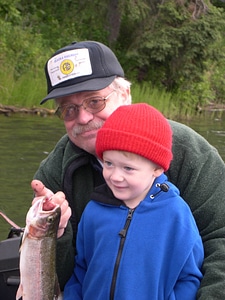 Grandson and grandfather catch a rainbow trout photo