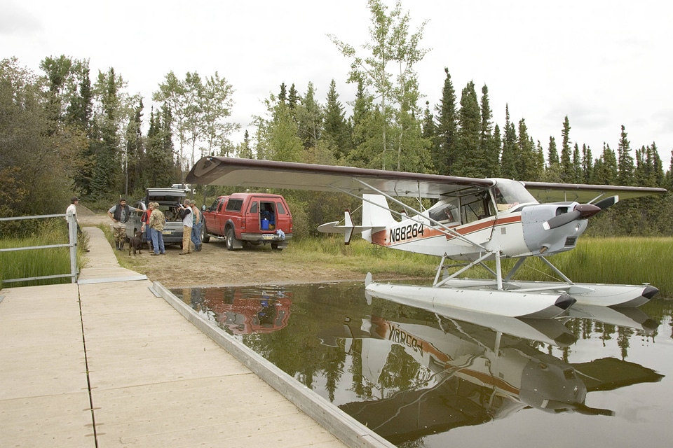 Seaplane docked while adults talk with U.S. Fish and Wildlife Service employee at Tetlin National Wildlife Refuge
