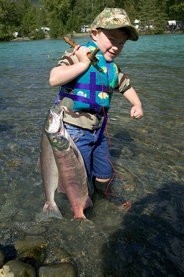 Young boy is proud of the salmon on his fish stringer