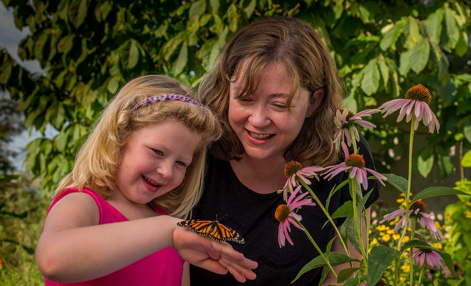 Mother and daughter looking at monarch