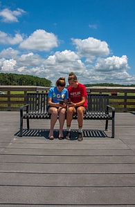 Students sittting on bench sharing cell phone pictures-3
