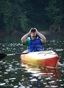 Man looking through binoculars while sitting in a kayak