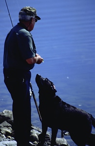 Man fishes with his dog at his side 