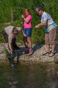 Older woman fishing with young redheaded girl, FWS employee netting trout-1