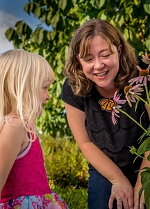 Mother and daughter look at monarch on flower-3