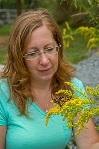 Woman with monarch butterfly on goldenrod flowers