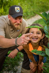 FWS employee shows young girl a Monarch chrysalis