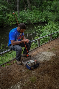 Young man sitting on rail preparing to fish