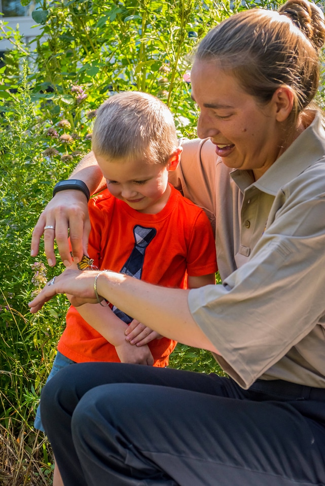 Child and fws employee look at monarch
