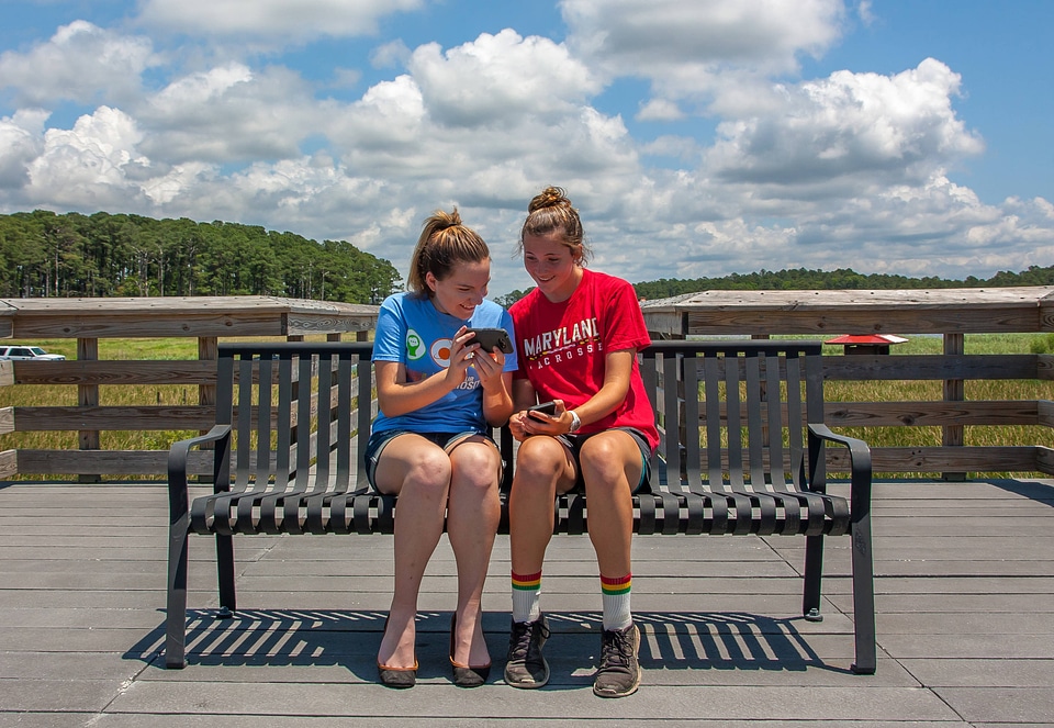 Students sittting on bench sharing cell phone pictures-1