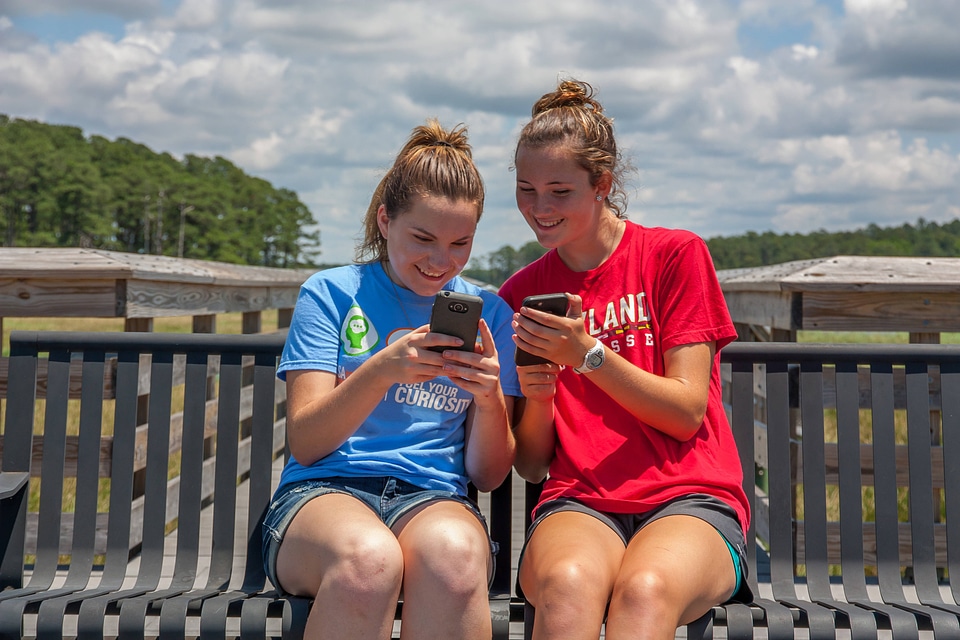 Students sittting on bench sharing cell phone pictures-1