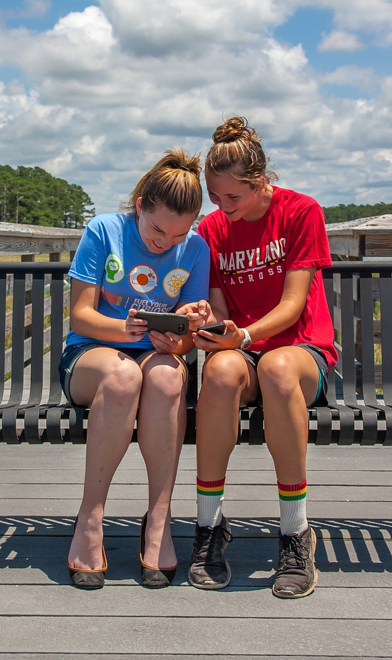 Students sittting on bench sharing cell phone pictures-3