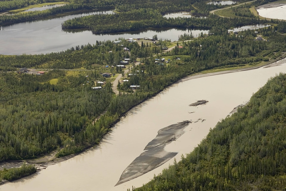 Aerial shot of river winding through forest and around village in Tetlin National Wildlife Refuge