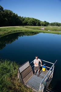 Fishery Biologist adjusts water flow to fish pond-4