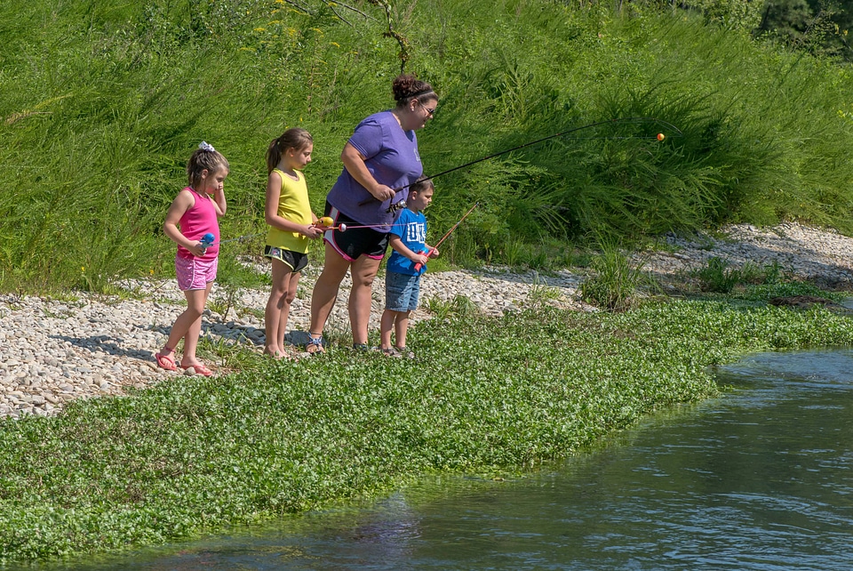 Family along steam with fishing rods