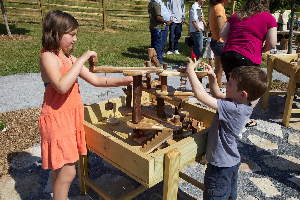 Children playing outside with a wooden interactive toy