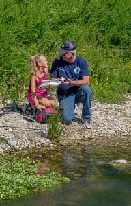 Older man and young girl look at rainbow trout-1