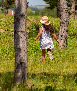Child in hat running between trees photo
