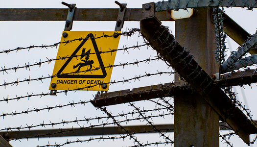 Danger of death sign behind barbed wire photo