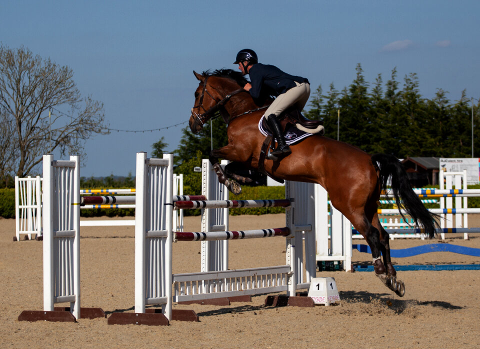Man on horse back jumping in show
