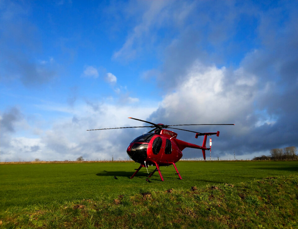 Red 4 seat helicopter on grass