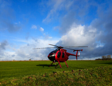 Red 4 seat helicopter on grass
