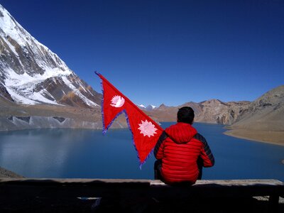 Man at Tilicho Lake with national flag photo