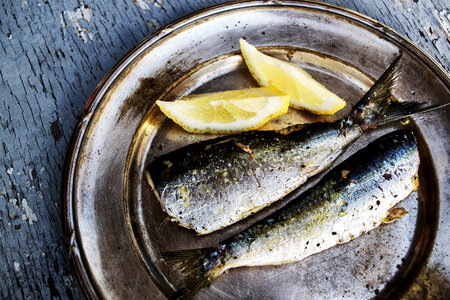 Sardines and Lemon on a Metal Plate with Broken Paint Wooden Background