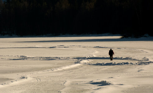 Lonely Man Walks Away on Frozen Lake photo