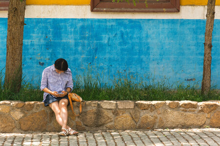 Young woman sitting with phone on the street photo