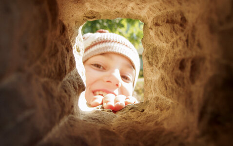 Little smiling girl playing hide and seek photo